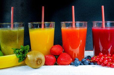 Colofrul fresh pressed fruit juices in tall glasses with fruits