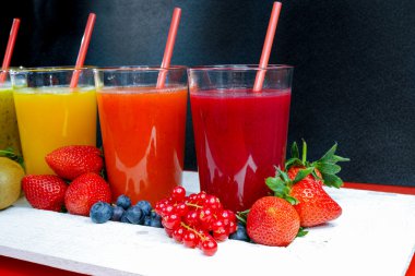 Colofrul fresh pressed fruit juices in tall glasses with fruits