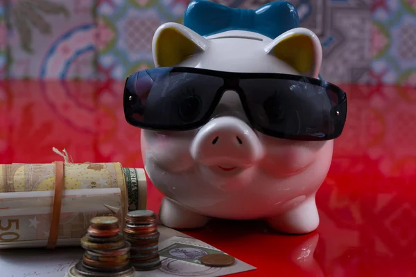 Piggy bank with black sunglasses and rolls cash — Stock Photo, Image