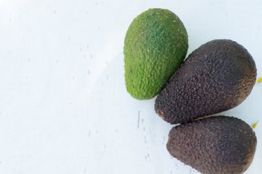 Beyaz ahşap zemin üzerine yeşil olgun avokado