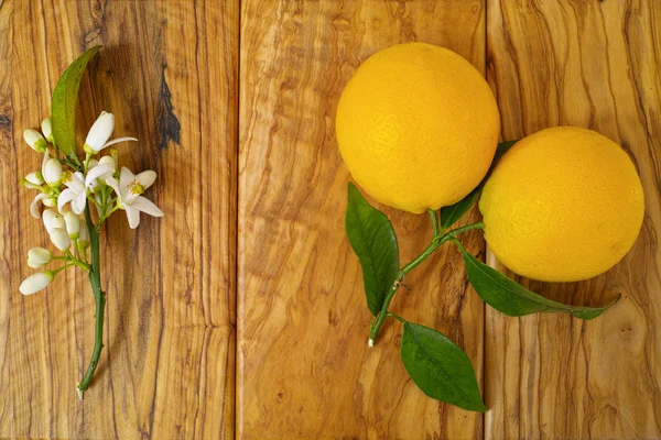 Fresh oranges with leaves and orange tree flowers on olive wood — Stock Photo, Image