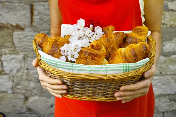 Young woman holding a wicker basket of fresh baked croissants — Stock Photo, Image