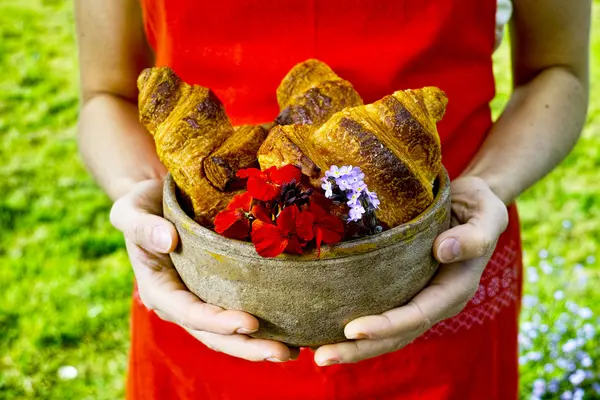 Young woman holding a plate of fresh baked croissants — Stock Photo, Image