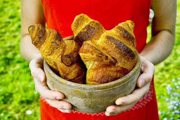 Young woman holding a plate of fresh baked croissants — Stock Photo, Image