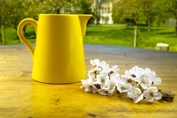 Lata de cerámica amarilla y flores en mesa de madera vieja — Foto de Stock