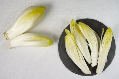 Bir gri taş tahta üzerine yerleştirilmiş taze hindiba salata yaprakları