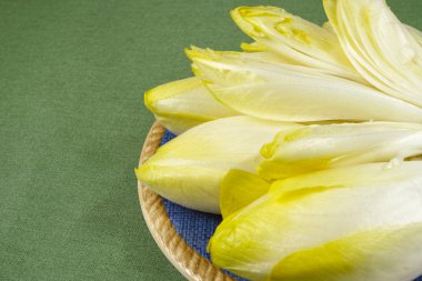 Mavi bir tabağa yerleştirilmiş taze hindiba salata yaprakları 