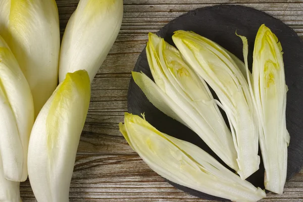 Feuilles de salade de chicorée fraîche placées sur une planche de pierre grise — Photo