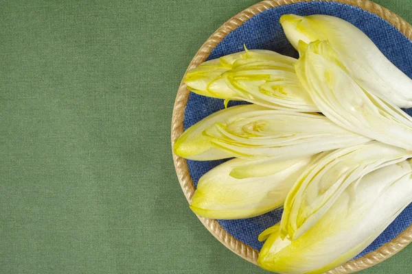 Feuilles de salade de chicorée fraîche placées sur une assiette bleue — Photo