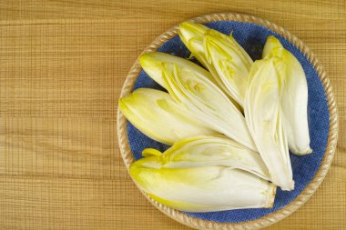 Mavi bir tabağa yerleştirilmiş taze hindiba salata yaprakları 