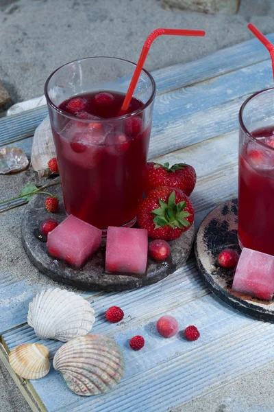 Freshly pressed juice mix with ice cubes on the beach