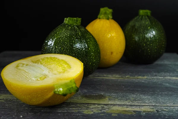 Gul och grön zucchini (Cucurbita pepo) på en mörk bakgrund — Stockfoto