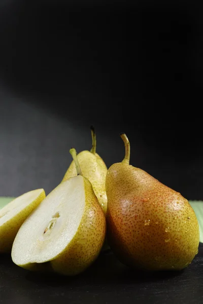 Fresh ripe organic pears on green and black background — Stock Photo, Image
