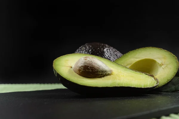 Färsk mogen ekologisk avocado på grönt och svart bakgrund — Stockfoto