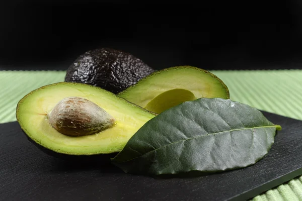 Färsk mogen ekologisk avocado på grönt och svart bakgrund — Stockfoto