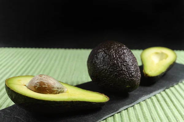 Świeży dojrzałe awokado organiczne na zielone i czarne tło — Zdjęcie stockowe