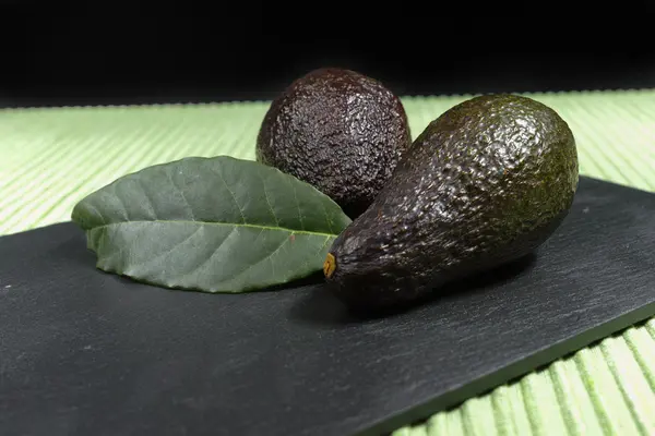 Färsk mogen ekologisk avocado på grönt och svart bakgrund — Stockfoto