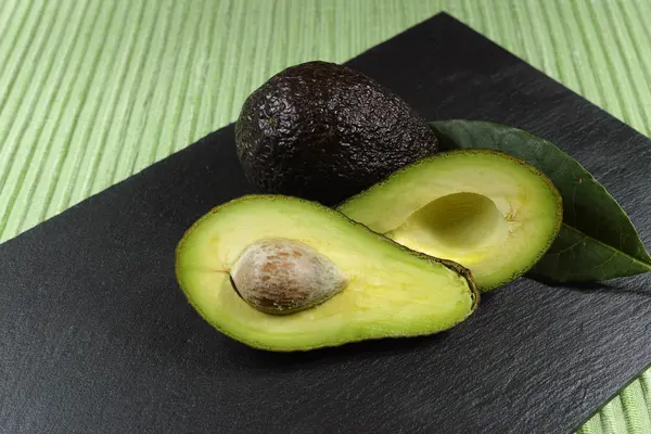 Färsk mogen ekologisk avocado på grönt och svart bakgrund — Stockfoto