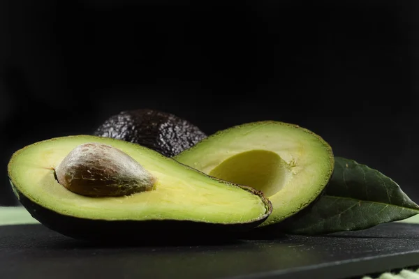 Färsk mogen ekologisk avocado på grönt och svart bakgrund — Stockfoto