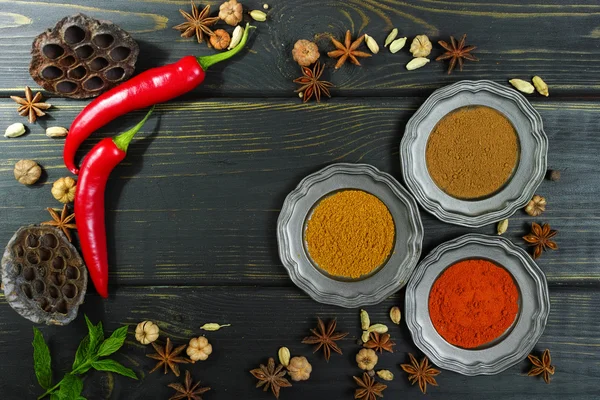 Färgglada indiska kryddor på svart bordsskiva av trä — Stockfoto