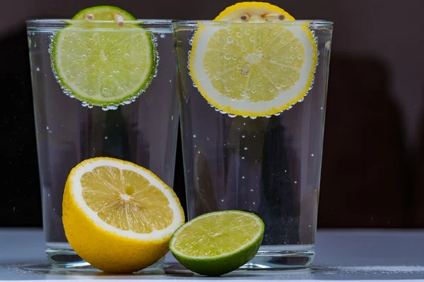 Glass with cold sparkling mineral water, lime and lemon — Stock Photo, Image