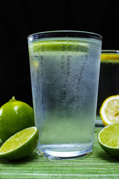 Glass with cold sparkling mineral water with fresh lime — Stock Photo, Image