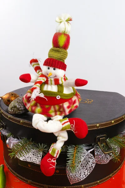 Funny snowman sits on vintage brown coffer with white christmas decoration — Stock Photo, Image