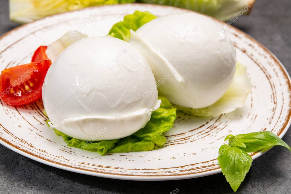 cheese collection, balls on soft white mozzarella buffala cheese served with green cos lettuce and tomato close up