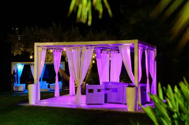 Geceleri yeşil tropikal bahçede beyaz lüks bir teras.