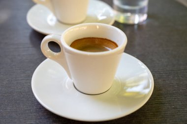 Kapalı kafedeki terasta koyu siyah espresso içiyorum.