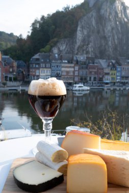 Bir bardak Belçika manastırı birası ve trapist birayla yapılan peynirleri tatmak ve Belçika, Dinant 'taki Maas nehri manzaralı güzel otlar.