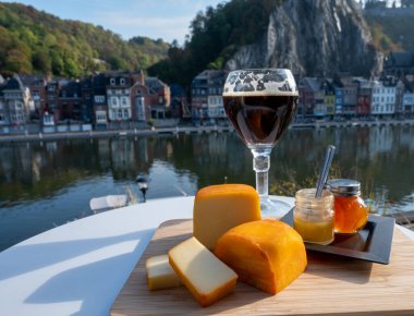 Bir bardak Belçika manastırı birası ve trapist birayla yapılan peynirleri tatmak ve Belçika, Dinant 'taki Maas nehri manzaralı güzel otlar.