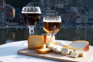 Bir bardak Belçika manastırı birası ve trapist birayla yapılan peynirleri tatmak ve Belçika, Dinant 'taki Maas nehri manzaralı güzel otlar.