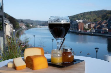 Bir bardak Belçika manastırı birası ve trapist birayla yapılan peynirleri tatmak ve Belçika, Dinant 'taki Maas nehri manzaralı güzel otlar.