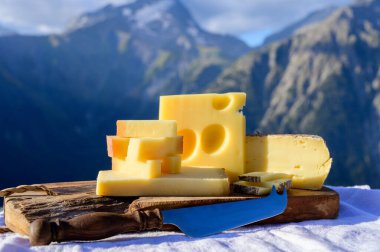 Peynir koleksiyonu, Fransız beaufort, abondance, emmental, tomme de savoie cheeses Savoy bölgesinde açık havada servis edilir, yaz aylarında Alp dağlarının zirveleri arka plandadır.