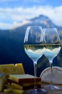 Fransa 'nın Savoy bölgesinden lezzetli peynir ve şarap, Beaufort, abondance, emmental, tomme ve reblochon de savoie peynirleri ve yazın açık havada sunulan beyaz şarap arka planda Alp dağlarının zirveleri