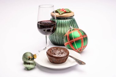 Popüler İngiliz noel yemeği, bir bardak kaliteli şarap ve arka planda izole edilmiş noel süslemesi olan sıcak çikolatalı pasta.