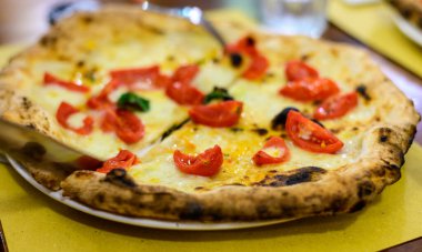 İtalyan pizzası, mozzarella peyniri, küçük kırmızı domates ve taze fesleğen.