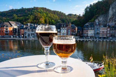 Koyu ve güçlü Belçika manastırı birası içmek güneşli bir günde Maas nehri manzaralı güzel manzaralı Belçika Dinant, Belçika