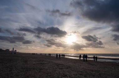 Hollanda 'da Zandvoort yakınlarında, Kuzey Denizi' nin geniş kumlu sahillerinde yürüyen kimliği belirsiz insanlar.