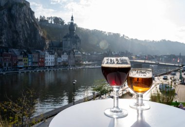 Koyu ve güçlü Belçika manastırı birası içmek güneşli bir günde Maas nehri manzaralı güzel manzaralı Belçika Dinant, Belçika
