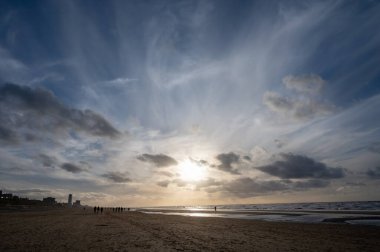 Hollanda 'da Zandvoort yakınlarında, Kuzey Denizi' nin geniş kumlu sahillerinde yürüyen kimliği belirsiz insanlar.