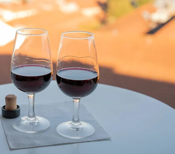 Tasting of different fortified dessert ruby, tawny port wines in glasses with view on Douro river, porto lodges of Vila Nova de Gaia and city of Porto, Portugal, on sunset