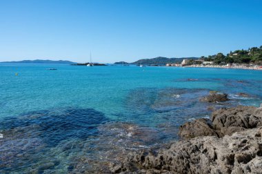 Fransız Riviera 'sında yaz tatili, Akdeniz' in berrak masmavi suları Le Lavandou, Var, Provence, Fransa yakınlarındaki Saint Clair 'de beyaz kumlu plajlar.