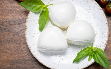 Peynir koleksiyonu, beyaz İtalyan peynirli mozzarella topları, kırmızı vişneli domates ve taze fesleğen yapraklarıyla servis ediliyor.