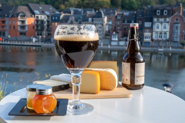 Koyu ve güçlü Belçika manastırı birası içmek güneşli bir günde Maas nehri manzaralı güzel manzaralı Belçika Dinant, Belçika