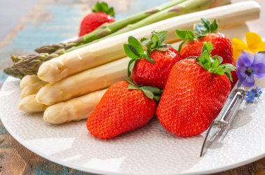 Hollanda 'da bahar mevsimi, yüksek kaliteli Hollanda beyaz kuşkonmazı, taze kırmızı olgun çilekle yıkanmış ve soyulmuş.