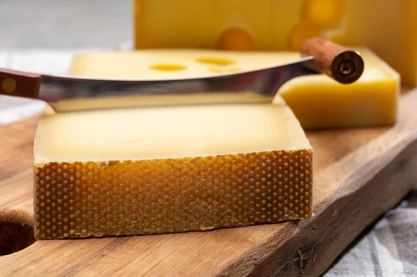 Swiss cheeses, block of medium-hard yellow cheese emmental or emmentaler with round holes and matured gruyere close up