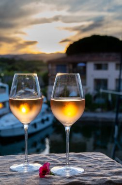 Yaz günbatımında yerel soğuk gül şarabının tadına bakmak arka planda liman, Provence, Var, Fransa