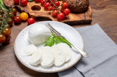 Peynir koleksiyonu, beyaz İtalyan peyniri mozzarellası yemek, kırmızı vişneli domates ve taze fesleğen yapraklarıyla servis edilmek.